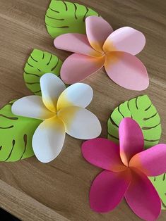 three paper flowers sitting on top of a wooden table