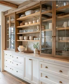 a kitchen with lots of white dishes on the shelves and cupboards in front of it