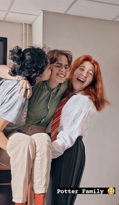 three women hugging each other while sitting in an office chair and smiling at the camera