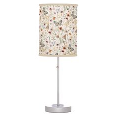 a table lamp with a white shade and floral print on it, sitting on a metal base