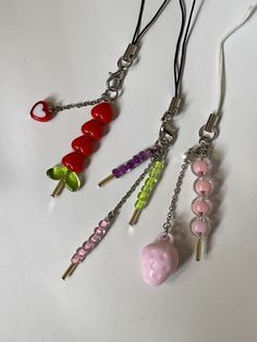 four different colored beads are attached to silver earwires on a white table top