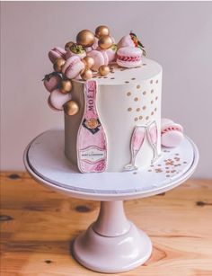 a white cake with pink frosting and gold decorations on top, sitting on a pedestal