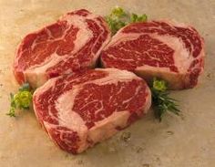 a piece of raw meat sitting on top of a white plate next to some parsley