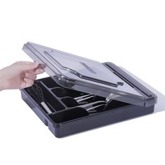 a person's hand is holding an open plastic tray with utensils in it