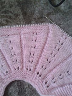 a pink knitted sweater with holes in the middle and an openwork design on the bottom