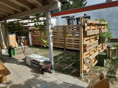 a wooden fence sitting on top of a grass covered yard next to a building and potted plants