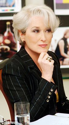 an older woman sitting at a desk with her hand on her chin and looking off to the side