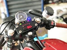 a close up of the speedometer and gauges on a red motorcycle parked in a garage