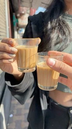 a woman holding two glasses filled with liquid