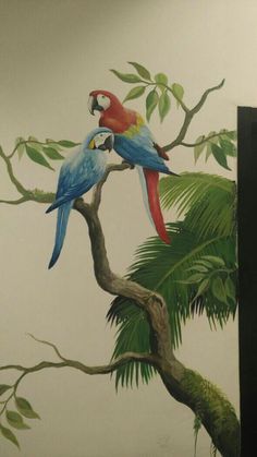 two parrots sitting on top of a tree branch in front of a wall mural