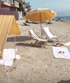 two beach chairs and an umbrella on the sand