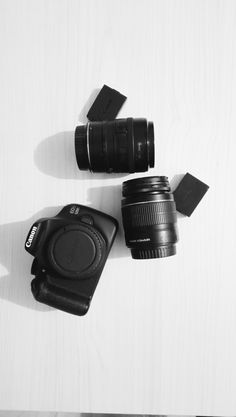 two cameras sitting next to each other on top of a white table with black objects