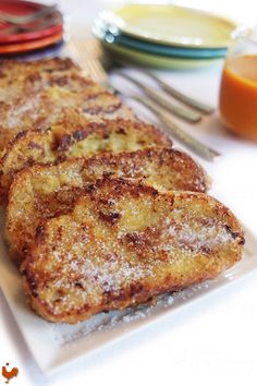 three pieces of fried food on a white plate next to orange juice and silverware