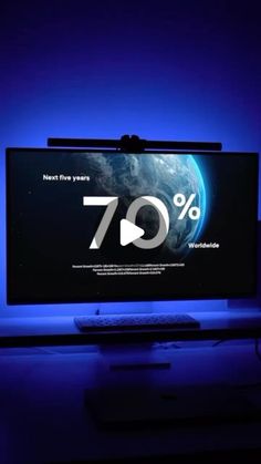 a flat screen tv sitting on top of a desk in front of a blue light