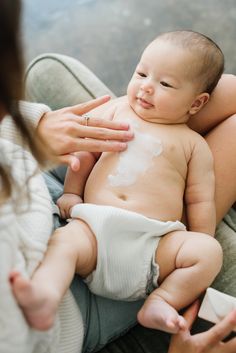 a woman holding a baby in her arms and touching it's face with the other hand