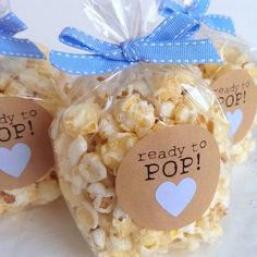 three bags filled with popcorn sitting on top of a white table covered in blue ribbon