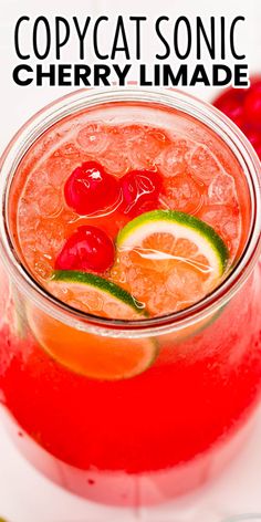 a close up of a drink in a glass with cherries and lime on the rim