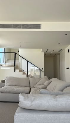 a living room filled with lots of furniture next to a stair case in front of a window