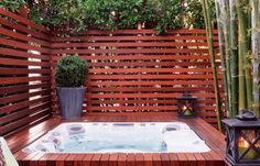 a hot tub sitting on top of a wooden deck next to a bamboo planter