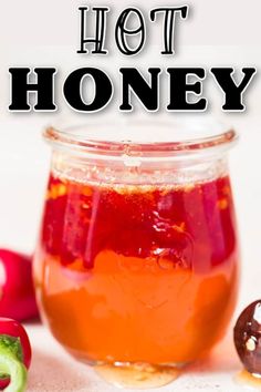 a jar filled with hot honey sitting next to some sliced vegetables and an eggplant