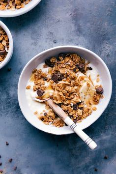 two bowls filled with granola and yogurt on top of a blue surface