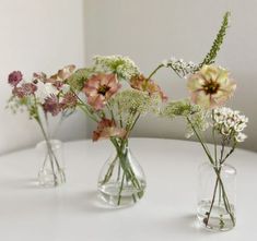 three glass vases with flowers in them on a table