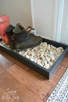 a pair of shoes sitting on top of rocks in a black shoe box with white pebbles