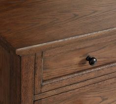 a close up of a wooden dresser with black knobs on the top and bottom drawers