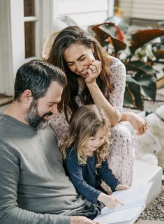 a man, woman and child sitting on a couch looking at a piece of paper