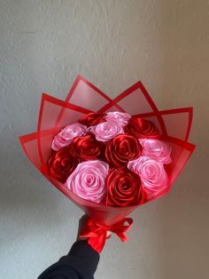 a hand holding a bouquet of red and pink roses