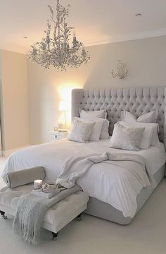 a bedroom with a chandelier and white bedding