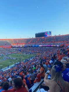 an orange and blue stadium filled with people watching a football game on a sunny day