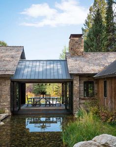 a house with a pond in front of it and stone walls around the back yard