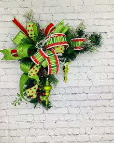 a green and red christmas wreath hanging on a brick wall next to a white brick wall