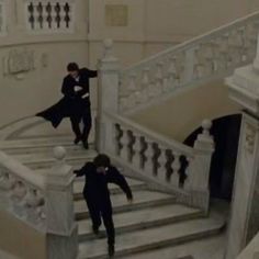 two people are walking down the stairs in a building