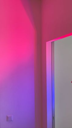 a bathroom with pink and blue lights on the wall, and a mirror in the corner