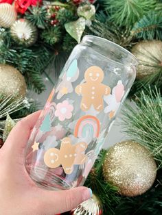 someone holding up a glass with gingerbreads and rainbows on it in front of a christmas tree