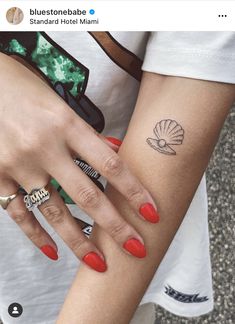 two women with red nails and matching rings on their arms, both holding each other's hands