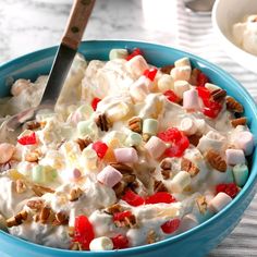 a blue bowl filled with fruit and nuts on top of a table next to a spoon