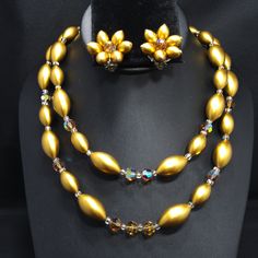 *Description: This is a beautiful mid-century necklace and earring set from the late 1950s. The colors and style are representative of this time period with the large metallic pearled finish oval beads with topaz Austrian Crystals as accent beads. The matching earrings have one crystal in the middle and six of the gold metallic beads around the center in a flower design. The necklace has aurora borealis rhinestone bars near each end. This is a great mid-century set to add to your favorite vintag Mid-century Handmade Wedding Jewelry, Vintage Gold Beaded Necklaces For Wedding, Vintage Gold Beaded Wedding Necklaces, Vintage Wedding Gold Beaded Necklaces, Vintage Polished Beads Jewelry For Wedding, Vintage Gold Jewelry With Polished Beads, Vintage Gold Jewelry With Large Beads, Vintage Beaded Jewelry For Party, Vintage Polished Yellow Beads Jewelry