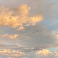 two people standing on the beach flying a kite in the sky with clouds behind them