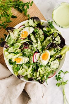 a white bowl filled with lettuce, eggs and radishes on top of a table