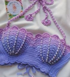 a crocheted bra with pearls on it and a book laying next to it