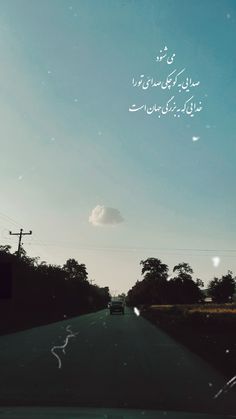 the sky is blue and there are trees on the side of the road in arabic writing