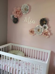 a baby's room with pink walls and white crib, flowers on the wall