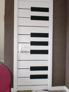 a door with black and white piano keys painted on the front, behind a pink chair