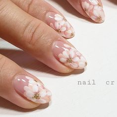 a woman's hand with pink and white flowers painted on her nails, next to an open notebook