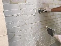 a man in white gloves painting a brick wall