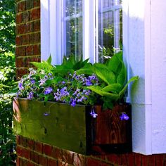 a window box filled with purple flowers next to a brick building