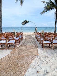 an outdoor ceremony setup on the beach with palm trees and chairs set up to look out at the ocean